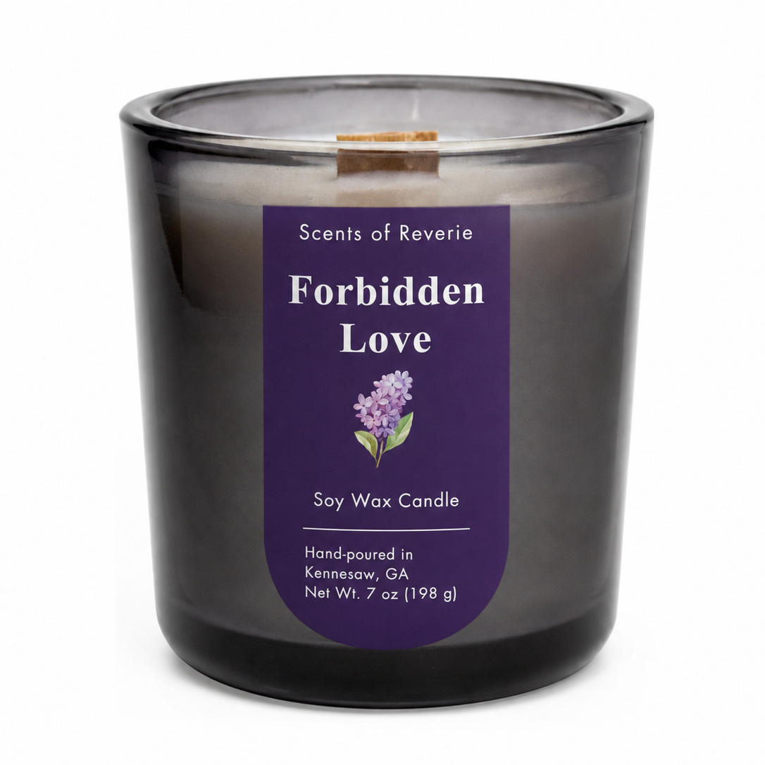 A dark gray smoky glass jar candle with a purple label reading 'Forbidden Love' by Scents of Reverie, on a white background.