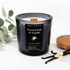 Black candle labeled 'Frosted Oak & Vanilla' with vanilla beans and a leaf on a white background