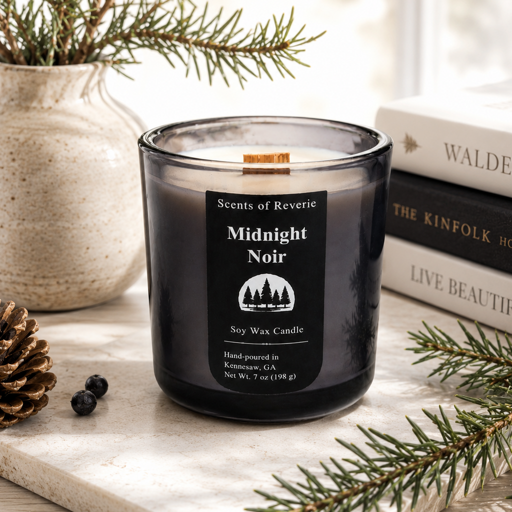 Candle labeled 'Midnight Noir' on a surface with decorative elements like books and a vase.