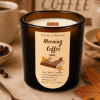 An amber glass soy wax candle labeled 'Morning Coffee' by Scents of Reverie, styled on a tabletop with coffee beans, a mug of coffee, autumn leaves, and a pastry.