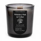 A 7 oz soy wax candle in a dark, translucent smoky gray glass jar with a black label reading 'Scents of Reverie Whiskey Oak & Cedar'.