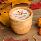 Pumpkin Praline candle with a wooden lid on a wooden surface with fall leaves.